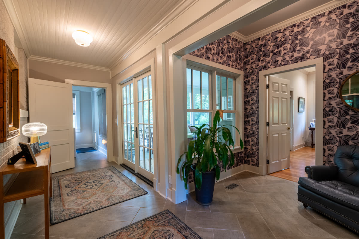 A sunroom addition with french doors, patterned wallpaper, and tile flooring.