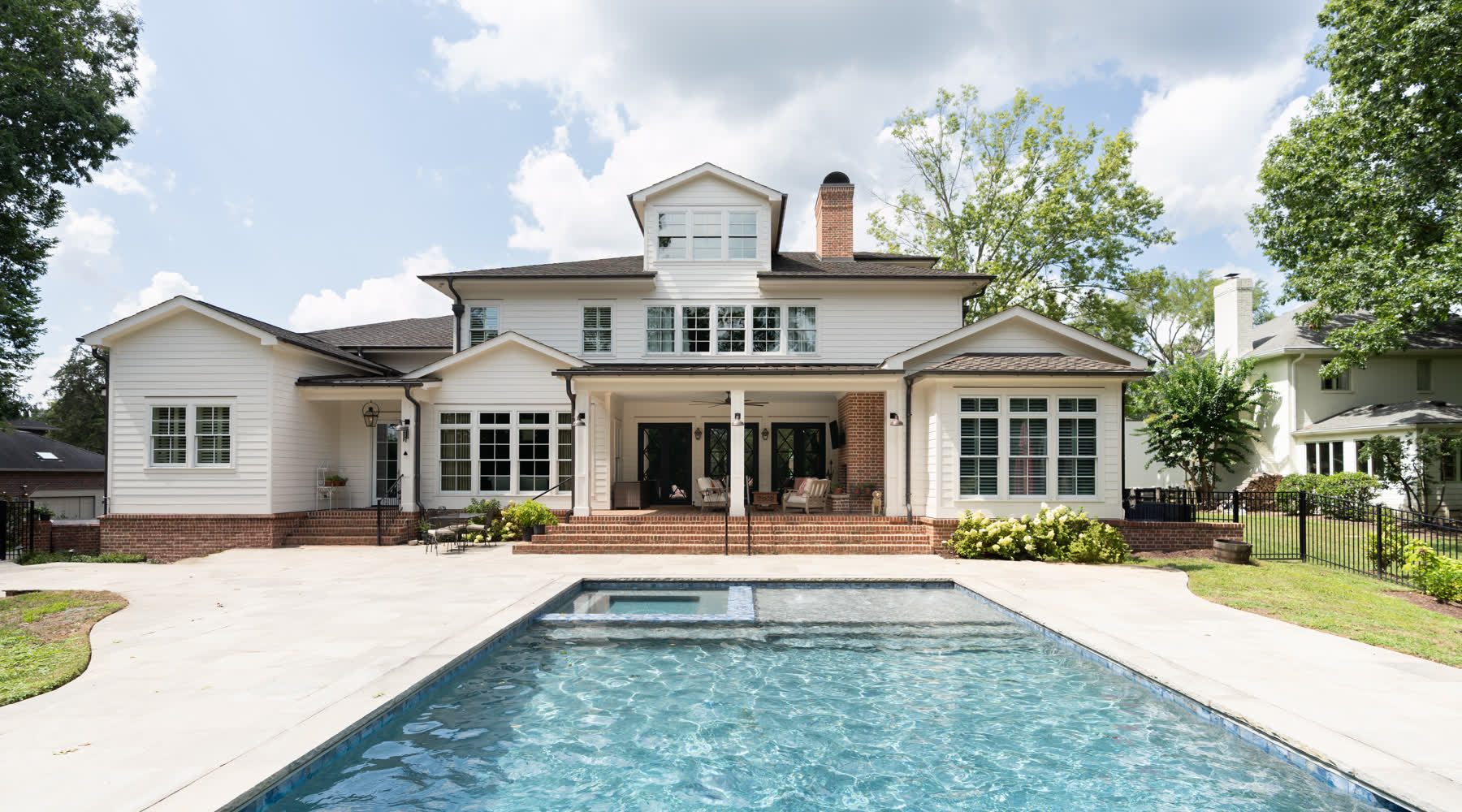 The rear elevation of a custom home overlooking a stone pool deck.