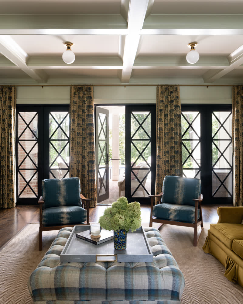 A living room with a beamed ceiling and paired french doors opening to a porch.